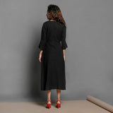 Back View of a Model wearing Black Handspun Cotton Surplice Neck Pleated Midi Dress