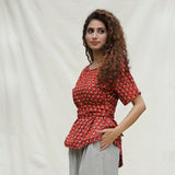 Left View of a Model wearing Brick Red Floral Block Printed Cotton Peplum Top