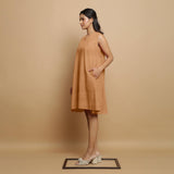 Left View of a Model wearing Desert Yellow Linen Embroidered Knee-Length Godet Dress