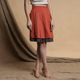 Right View of a Model wearing Orange and Brown Reversible Pleated Flared Skirt