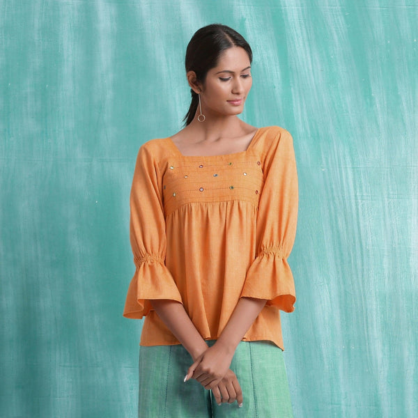 Front View of a Model wearing Orange Handspun Yoked Mirror Top