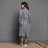 Back View of a Model wearing Slate Grey Handspun Cotton Knee Length Frilled Peasant Dress