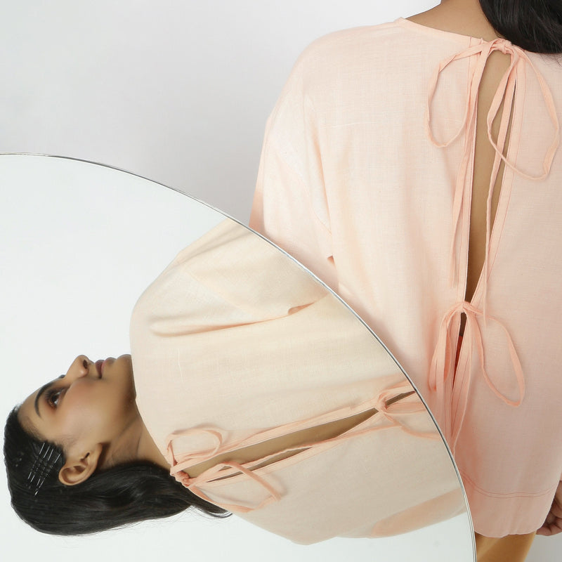 Back Detail of a Model wearing Powder Pink Vegetable Dyed Cotton Loose Fit Tie Neck Top